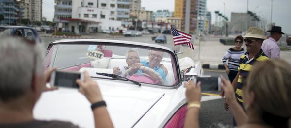 U.S. citizens pose for photos as they enjoy a ride in a vintage car at the seafront Malecon during a cultural exchange trip in Havana, September 28, 2015 - Sputnik International