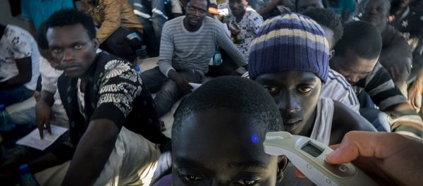 A member of Medecins Sans Frontieres (Doctors without borders - MSF) checks the temperature of a refugee onboard the Dignity 1 search and rescue vessel after they were rescued along with other migrants from their rubber boat by members of MSF in the Meditterranean sea off the coast of Libya on September 29, 2015 - Sputnik International