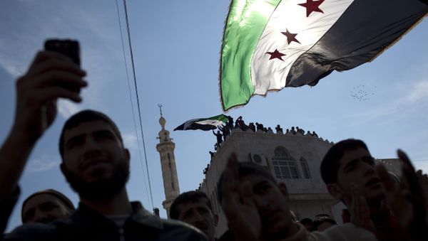 In this Friday, March 2, 2012 file photo, men hold revolutionary Syrian flags during an anti-government protest in a town in northern Syria. In this Friday, March 2, 2012 file photo, men hold revolutionary Syrian flags during an anti-government protest in a town in northern Syria. - Sputnik International
