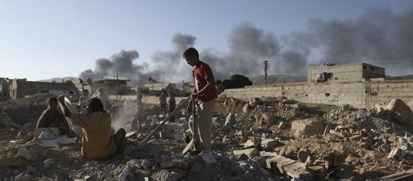 Children inspect rubble as smoke rises behind them during clashes between forces loyal to Syria's President Bashar al-Assad and the Army of Islam fighters, on the eastern mountains of Qalamoun overlooking the town of Douma, eastern Ghouta in Damascus September 19, 2015 - Sputnik International