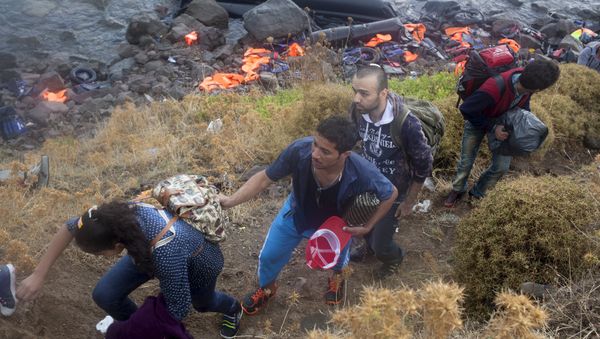 Syrian refugees climb a slope after arriving on an overcrowded dinghy under heavy rainfall on the Greek island of Lesbos after crossing a part of the Aegean Sea from the Turkish coast, September 28, 2015 - Sputnik International