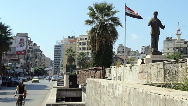 A man rides his bike past a statue of late Syrian president Hafez al-Assad, father of current President Bashar al-Assad, in the Syrian coastal city of Latakia on September 24, 2015 - Sputnik International