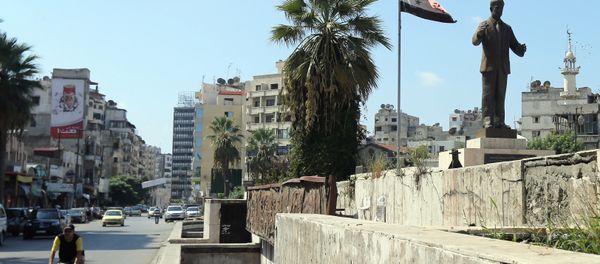 A man rides his bike past a statue of late Syrian president Hafez al-Assad, father of current President Bashar al-Assad, in the Syrian coastal city of Latakia on September 24, 2015 - Sputnik International