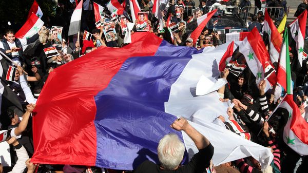 Pro-Syrian regime protesters wave a large Russian flag during a demonstration - Sputnik International