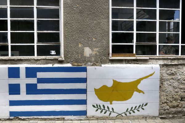 A representation of the Greek, left, and Cyprus flags are painted on a wall as a Greek Cypriot soldier is seen inside a guard post by the U.N controlled buffer zone as they cuts across the Cypriot divided capital Nicosia A representation of the Greek, left, and Cyprus flags are painted on a wall as a Greek Cypriot soldier is seen inside a guard post by the U.N controlled buffer zone as they cuts across the Cypriot divided capital Nicosia - Sputnik International