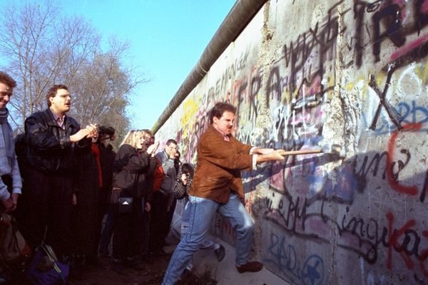 An unidentified West Berliner swings a sledgehammer, trying to destroy the Berlin Wall near Potsdamer Platz, on November 12, 1989, where a new passage was opened nearby - Sputnik International