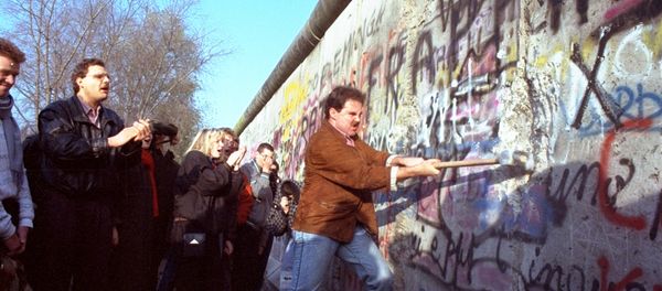 An unidentified West Berliner swings a sledgehammer, trying to destroy the Berlin Wall near Potsdamer Platz, on November 12, 1989, where a new passage was opened nearby - Sputnik International