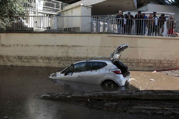 People look at an abandoned car trapped in muddy waters near an underpass after flooding caused by torrential rain in Cannes, France - Sputnik International