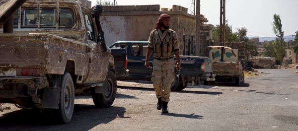 A Free Syrian Army fighter walks near military vehicles during what they said was preparations for an operation to strike at forces loyal to Syria's president Bashar Al-Assad in order to break a siege on the city of Beit Gin located in western countryside of Damascus in Deraa, Syria September 30, 2015 - Sputnik International