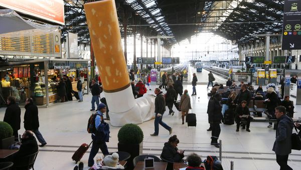 People pass by a giant mock-up discarded cigarette displayed on the ground at the Gare de Lyon railway station in Paris, on December 4, 2012. - Sputnik International