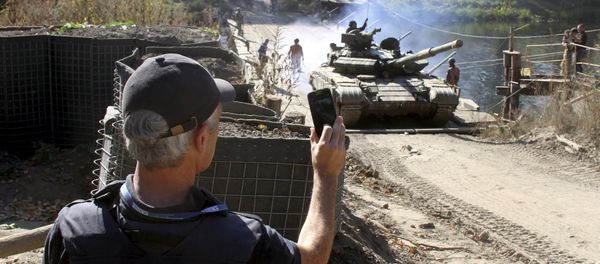 A member of the Organization for Security and Co-operation in Europe (OSCE) monitors the withdrawal of tanks of the Ukrainian armed forces near the village of Nyzhnje in Luhansk region, Ukraine, October 5, 2015 - Sputnik International