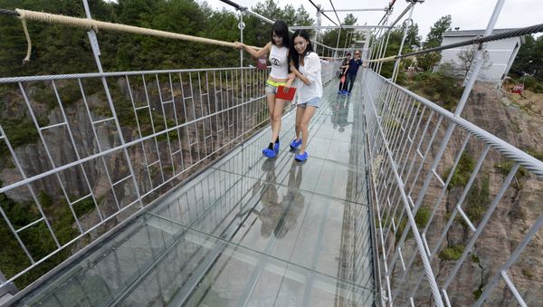 Tourists look down as they walk on a glass suspension bridge at the Shiniuzhai National Geo-park in Pinging county, Hunan province, China, September 24, 2015 Tourists look down as they walk on a glass suspension bridge at the Shiniuzhai National Geo-park in Pinging county, Hunan province, China, September 24, 2015 - Sputnik International