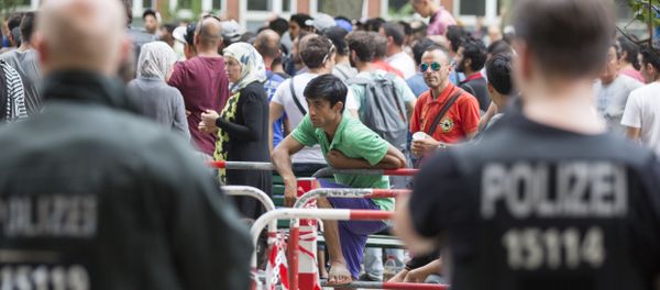 Police stand next to asylum seekers waiting in front of the reception center for refugees in Berlin, Germany, Friday, Aug. 7, 2015. Police stand next to asylum seekers waiting in front of the reception center for refugees in Berlin, Germany, Friday, Aug. 7, 2015. - Sputnik International