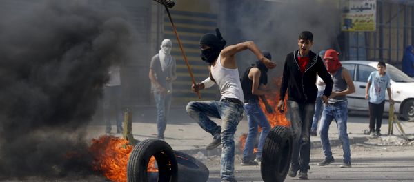 A Palestinian protester moves a burning tyre during clashes with the Israeli army at Qalandia checkpoint near occupied West Bank city of Ramallah October 6, 2015 - Sputnik International