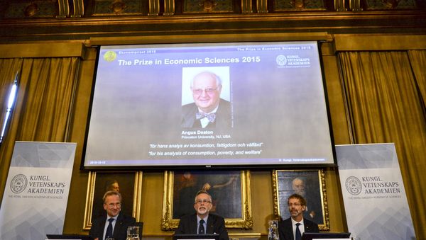 A picture of British economist Angus Deaton, winner of the 2015 economics Nobel Prize, is seen on a screen as Goran K. Hansson (C), permanent secretary for the Royal Swedish Academy of Sciences, and Tore Ellingsen (L), chairman of the prize committee, and Jakob Svensson, member of the Academy, address a news conference at the Royal Swedish Academy of Science, in Stockholm, Sweden October 12, 2015 - Sputnik International