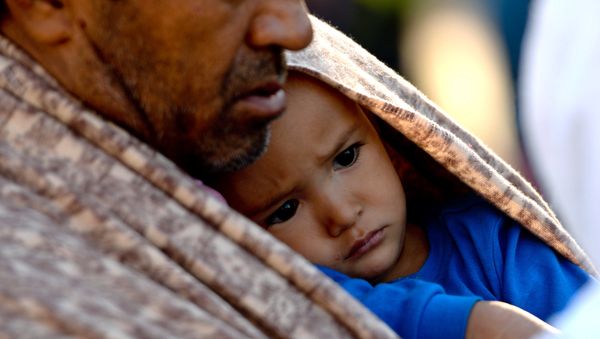 A migrant holds a child after their arrival at the railway station in Lehrte, near Hannover, northern Germany, Saturday, Oct. 3, 2015. - Sputnik International