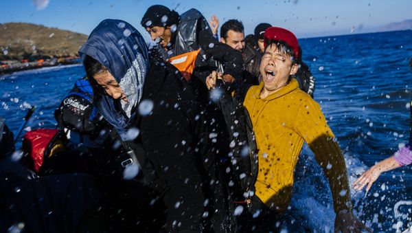 Refugees and migrants react as they arrive on a rubber boat on the Greek island of Lesbos, after crossing the Aegean sea from Turkey, on October 15, 2015. - Sputnik International