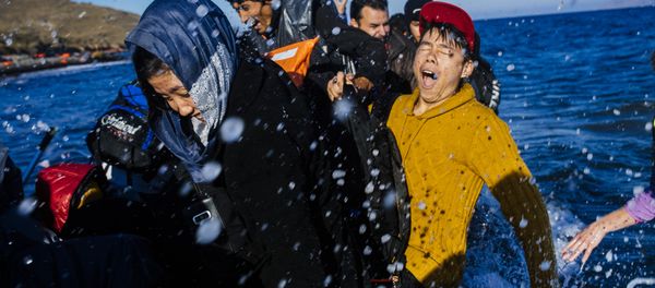 Refugees and migrants react as they arrive on a rubber boat on the Greek island of Lesbos, after crossing the Aegean sea from Turkey, on October 15, 2015. Refugees and migrants react as they arrive on a rubber boat on the Greek island of Lesbos, after crossing the Aegean sea from Turkey, on October 15, 2015. - Sputnik International