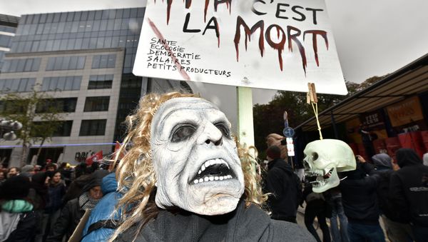 A protester with a mask demonstrates against the free trade agreement TTIP (Transatlantic Trade and Investment Partnership) during an EU summit in Brussels, Belgium on Thursday, Oct. 15, 2015. - Sputnik International