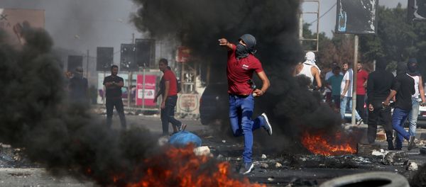 A Palestinian demonstrator hurls rocks towards Israeli border guards (unseen) during clashes at the Hawara checkpoint, south of the West Bank city of Nablus on October 16, 2015 - Sputnik International