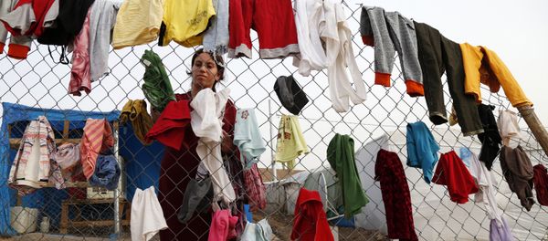 A Syrian refugee woman hangs laundry on a fence at an informal tented settlement in Irbil, northern Iraq. - Sputnik International