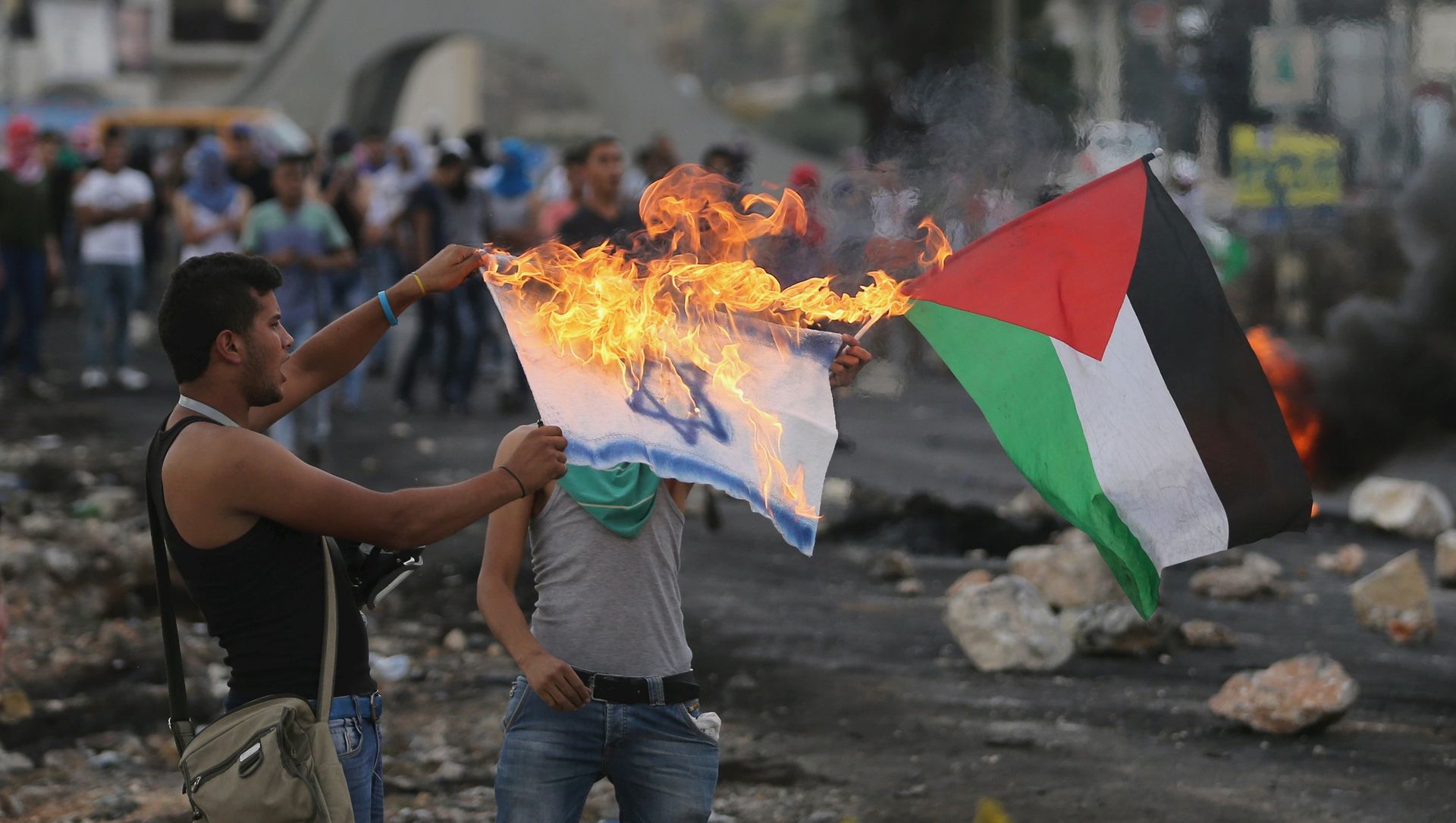 A protester burns a replica Israeli flag as another holds a Palestinian flag during clashes with the Israeli troops near the Jewish settlement of Bet El, near the West Bank city of Ramallah, 18 October 2015 A protester burns a replica Israeli flag as another holds a Palestinian flag during clashes with the Israeli troops near the Jewish settlement of Bet El, near the West Bank city of Ramallah, 18 October 2015 - Sputnik International, 1920, 17.05.2021