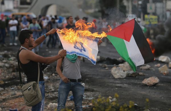A Palestinian protester burns a replica Israeli flag as another holds a Palestinian flag during clashes with the Israeli troops near the Jewish settlement of Bet El, near the West Bank city of Ramallah October 18, 2015 - Sputnik International