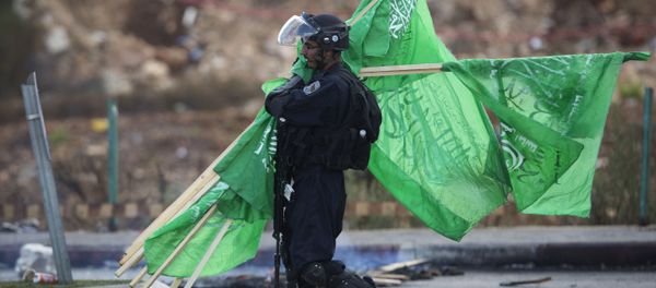 A member of the Israeli security forces carries flags of the Palestinian movement Hamas. A member of the Israeli security forces carries flags of the Palestinian movement Hamas. - Sputnik International