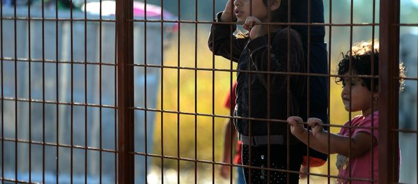 Children wait behind a fence to pass with their families in the southern Macedonian town of Gevgelija, Friday, Sept. 11, 2015. - Sputnik International