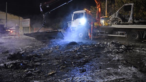 A man operates a crate, lifting up debris of burnt cars following a series of violent incidents on October 20, 2015 in Moirans, near Grenoble - Sputnik International