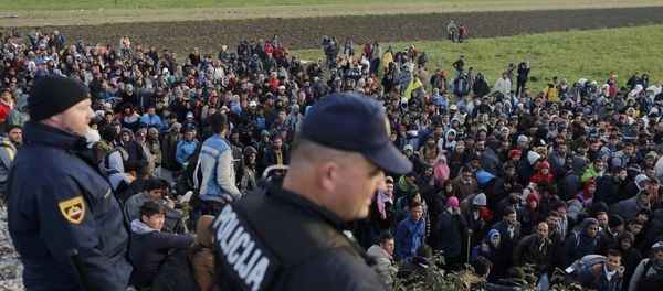 File Photo: Slovenian police officers watch as migrants walk from Dobova towards a transit camp in Brezice, Slovenia October 21, 2015 - Sputnik International