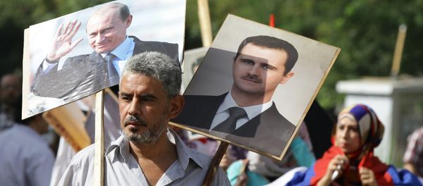 A Syrian man holding up portraits of President Bashar al-Assad and his Russian counterpart Valdimir Putin (L) joins several hundred people who gathered near the Russian embassy in Damascus on October 13, 2015 - Sputnik International