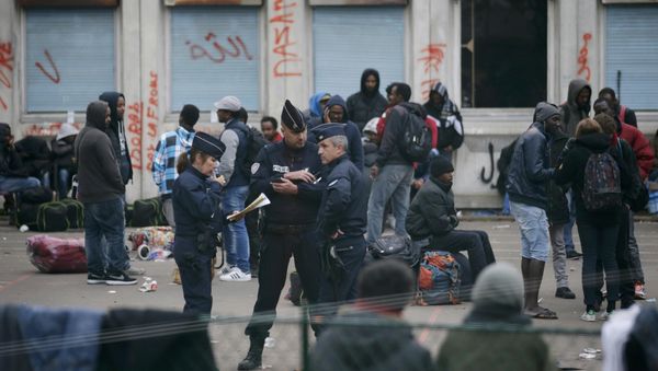 French police stand near migrants who gather in the courtyard of the Lycee Jean Quarre, an empty secondary school occuiped by hundred of migrants and asylum seekers in the 19th district in Paris, France, October 23, 2015 French police stand near migrants who gather in the courtyard of the Lycee Jean Quarre, an empty secondary school occuiped by hundred of migrants and asylum seekers in the 19th district in Paris, France, October 23, 2015 - Sputnik International