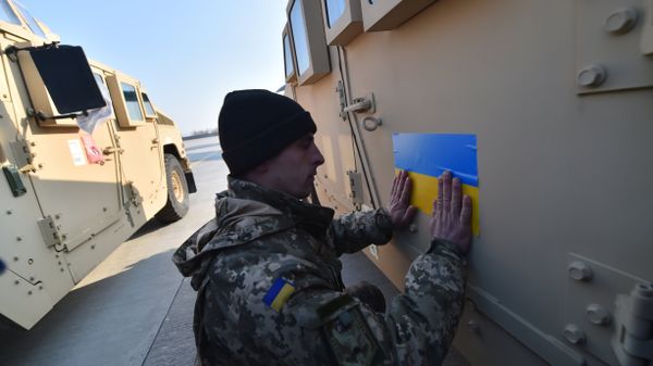 An Ukrainian serviceman sticks an Ukrainian flag on a Humvee at Kiev airport on March 25, 2015 during a welcoming ceremony of the first US plane delivery of non-lethal aid, including 10 Humvee vehicles - Sputnik International