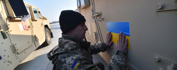 An Ukrainian serviceman sticks an Ukrainian flag on a Humvee at Kiev airport on March 25, 2015 during a welcoming ceremony of the first US plane delivery of non-lethal aid, including 10 Humvee vehicles - Sputnik International