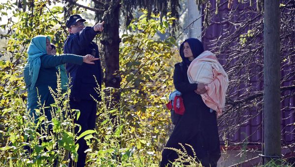 A Croatian police officer directs two women across the Sulta river as migrants and refugees travel across the Croatian-Slovenian border on October 20, 2015 near Kljuc Brdovecki A Croatian police officer directs two women across the Sulta river as migrants and refugees travel across the Croatian-Slovenian border on October 20, 2015 near Kljuc Brdovecki - Sputnik International