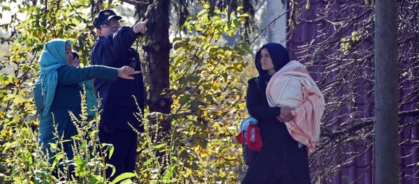 A Croatian police officer directs two women across the Sulta river as migrants and refugees travel across the Croatian-Slovenian border on October 20, 2015 near Kljuc Brdovecki - Sputnik International