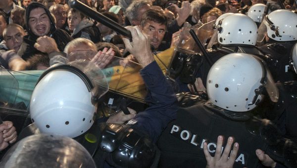 A riot policeman hits Montenegro's opposition leader Nebojsa Medojevic (facing camera, on R of baton) with a baton while dispersing protesters outside the parliament building in the capital Podgorica, Montenegro, October 17, 2015 - Sputnik International