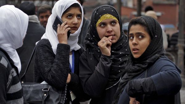 Kashmiri girls stand on a road divider after vacating their office buildings following an earthquake in Srinagar October 26, 2015.  - Sputnik International