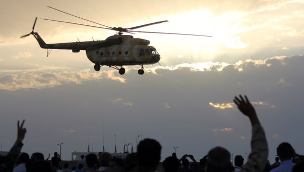 Libyans wave and flash the sign for victory at a military helicopter as flies during a military display in Libya's coastal city of Benghazi on May 15, 2012. - Sputnik International