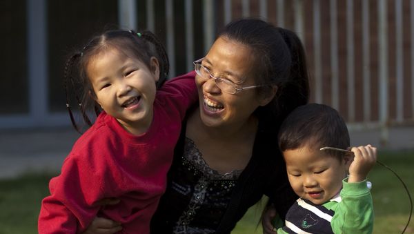 In this Monday, Oct. 17, 2011 photo, Wu Weiping, 35, plays with her daughter Wang Yile, 4, and her son Wu Yixiao, 2, near their home in Zhuji, in eastern China's Zhejiang province In this Monday, Oct. 17, 2011 photo, Wu Weiping, 35, plays with her daughter Wang Yile, 4, and her son Wu Yixiao, 2, near their home in Zhuji, in eastern China's Zhejiang province - Sputnik International