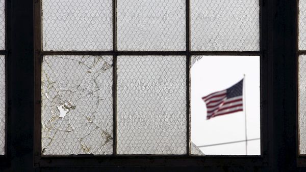 In this 2009 file photo, reviewed by the U.S. military, an American flag fluttering in the wind is pictured through a broken window from inside an airplane hangar used for media activities at Camp Justice, the site of the U.S. war crimes tribunal compound, at Guantanamo Bay U.S. Naval Base, Cuba, July 16, 2009 - Sputnik International