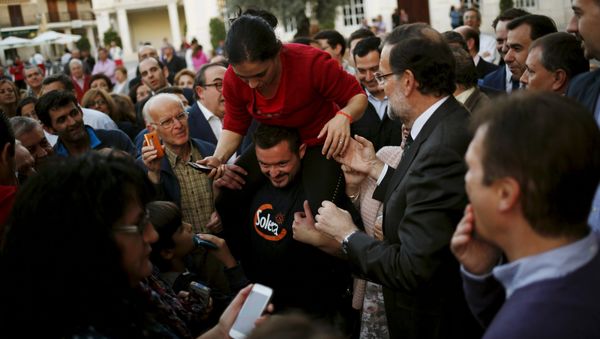 Prime Minister Mariano Rajoy (R) helps a woman to get down from the shoulders of a man before an electoral rally to open the electoral pre-campaign of the People's Party (PP) for the Spanish general elections, in Cabra, southern Spain, October 29, 2015 Prime Minister Mariano Rajoy (R) helps a woman to get down from the shoulders of a man before an electoral rally to open the electoral pre-campaign of the People's Party (PP) for the Spanish general elections, in Cabra, southern Spain, October 29, 2015 - Sputnik International
