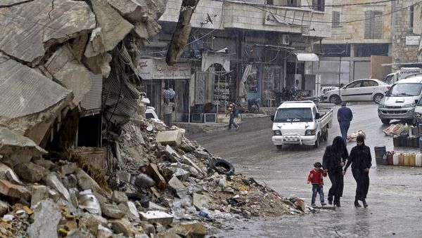 Civilians walk in the rain past a damaged building in the rebel-controlled area of Maaret al-Numan town in Idlib province, Syria October 28, 2015 - Sputnik International