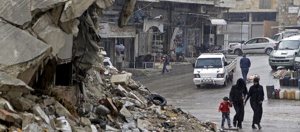 Civilians walk in the rain past a damaged building in the rebel-controlled area of Maaret al-Numan town in Idlib province, Syria October 28, 2015 - Sputnik International
