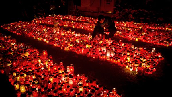 A riot policeman places a candle, collected from people waiting to pay respects to the victims of a fire, outside the Colectiv nightclub, in Bucharest, Romania. - Sputnik International