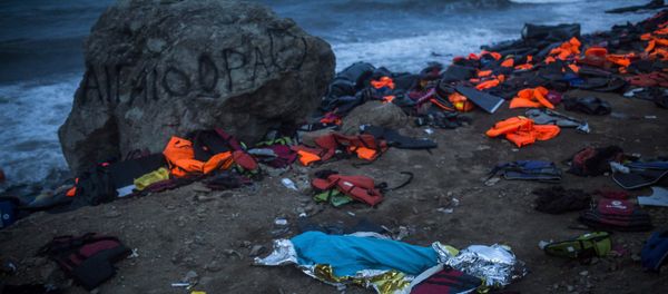 The body of a young man covered with a blue blanket remains on Eftalou beach after his dinghy capsized on the northeastern Greek island of Lesbos, Friday, Oct. 30, 2015. - Sputnik International