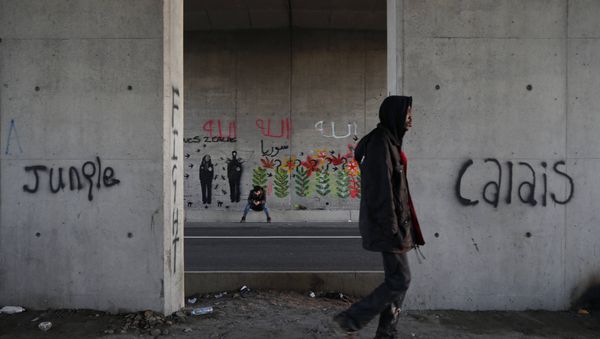 Migrants make their way along a road near graffiti with the words Jungle, Calais in Calais, France, October 20, 2015. - Sputnik International