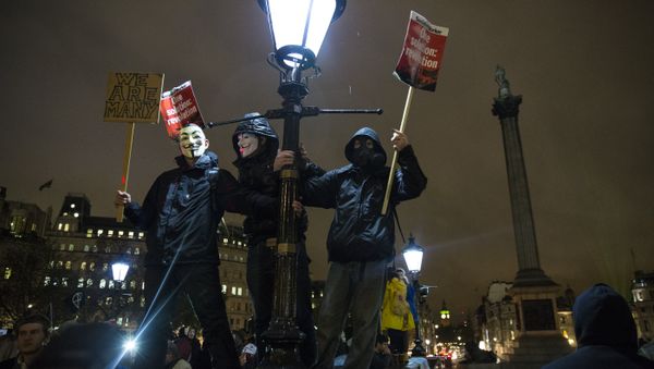 Anti-capitalist protesters wearing Guy Fawkes masks hold placards as they gather at Trafalgar Square ahead of the Million Masks March, organised by the group Anonymous, in London on November 5, 2015. - Sputnik International