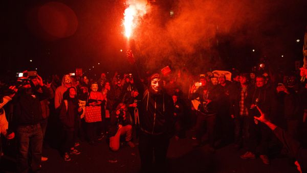 An anti-capitalist protester wearing aGuy Fawkes mask holds a lit flare during the Million Masks March, organised by the group Anonymous, near the Houses of Parliament in central London on November 5, 2015. - Sputnik International
